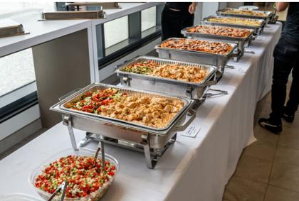 Chafing dishes lined up at a catered Eisenberg's event — schnitzel, rice, roasted vegetables and Israeli salad